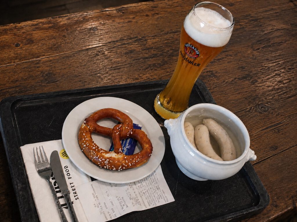 Beer, pretzel and traditional Bavarian Weißwurst on a rustic wooden table